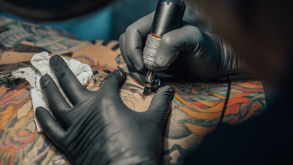 tattoo artist using tattoo ink to design someones arm