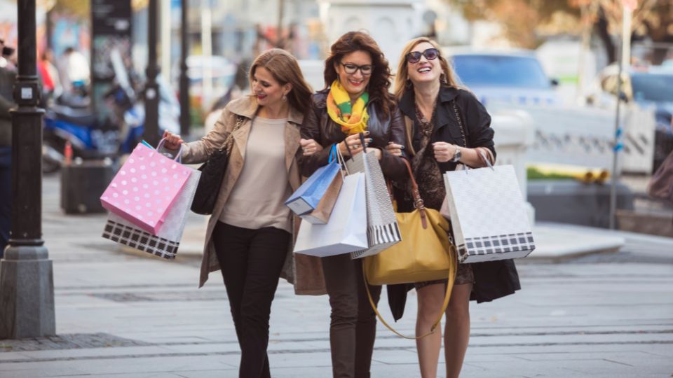 three women with lots of shopping bags buying clothes 