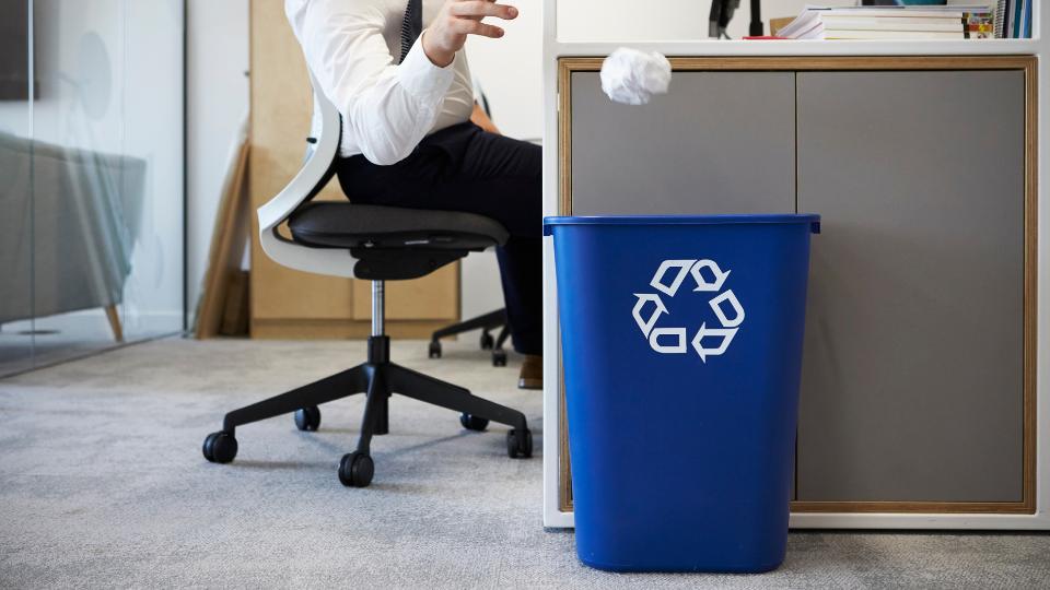 a office worker putting paper in the recycling bin