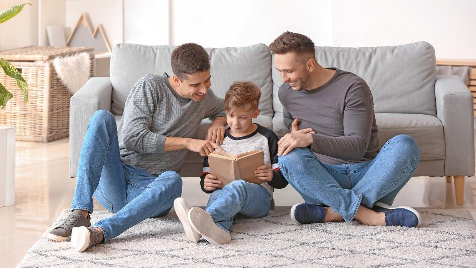 An LGBT male couple reading a book with their son 