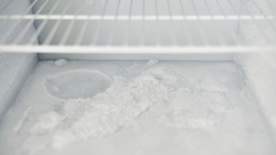 a frozen shelf in a broken fridge freezer