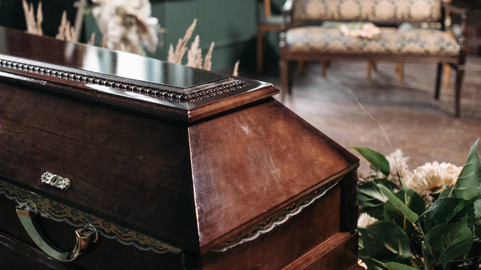 wooden coffin with flowers around it at a funeral home