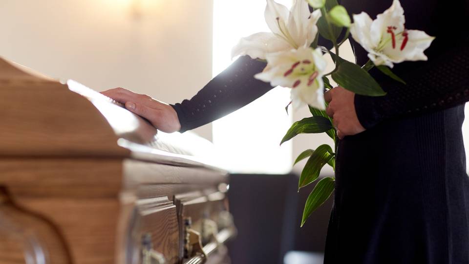 a person grieving at a funeral holding lillies 