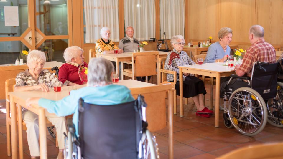 elderly people in a care home with cups of tea