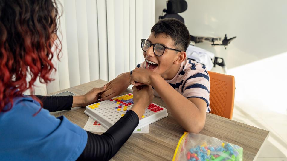 disabled child with nurse in care home playing with plastic toy 