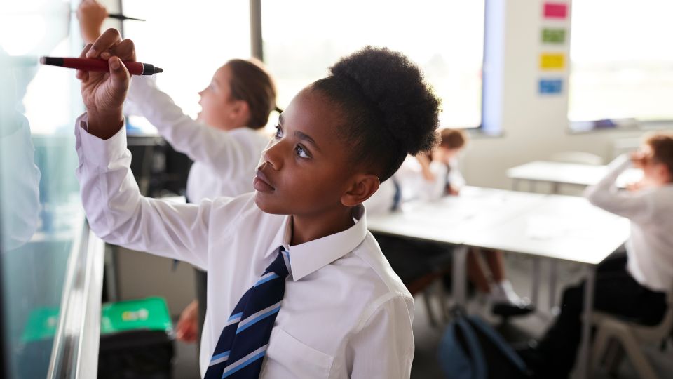 a child in a UK school writing on an interactive whiteboard