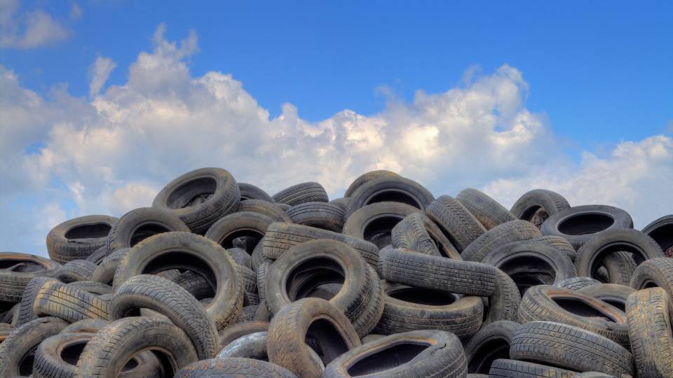A huge pile of recycled tyres with a blue sky in the background