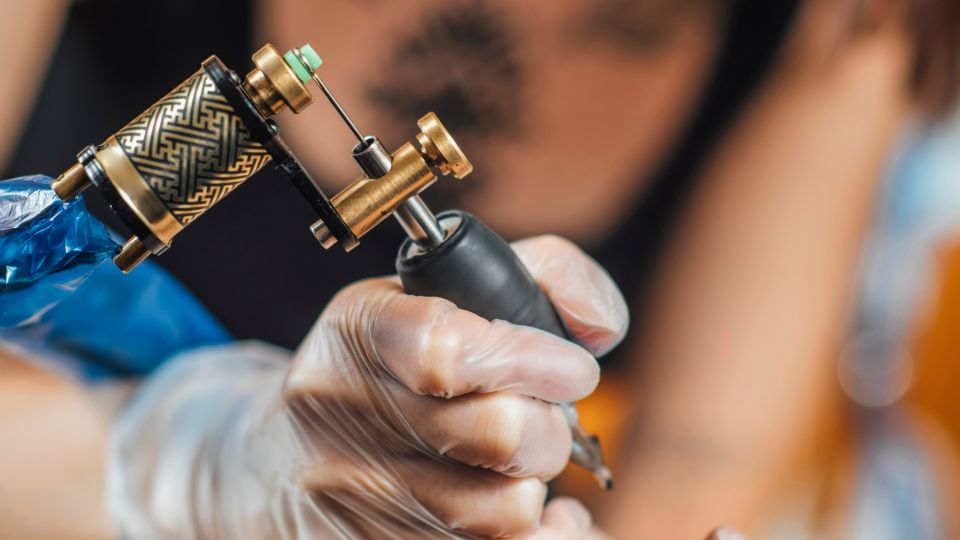 Tattoo artist wearing clear plastic gloves while tattooing. 