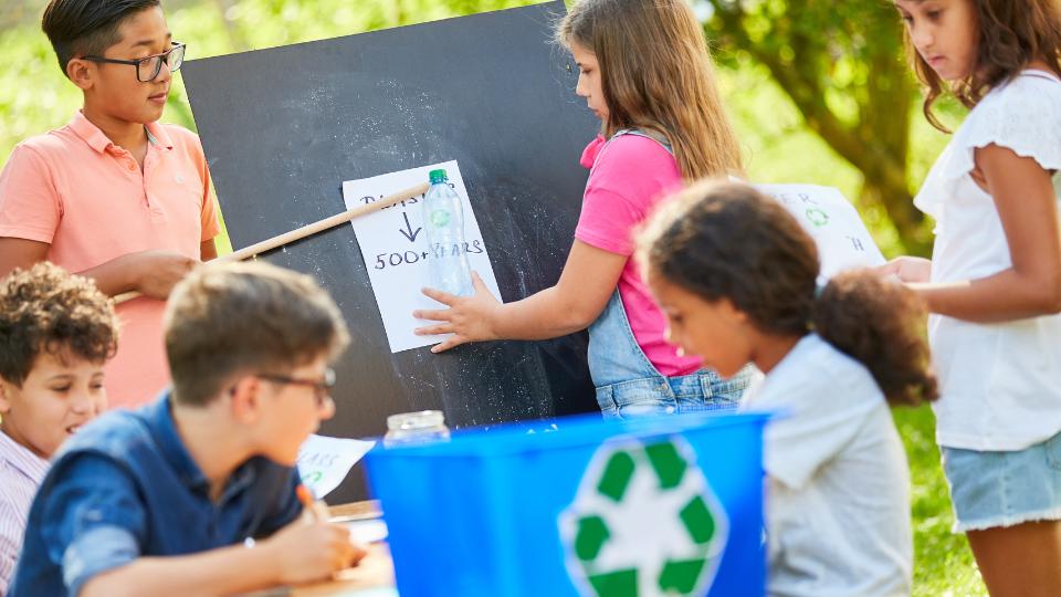 Kids learning about recycling with a blackboard outside