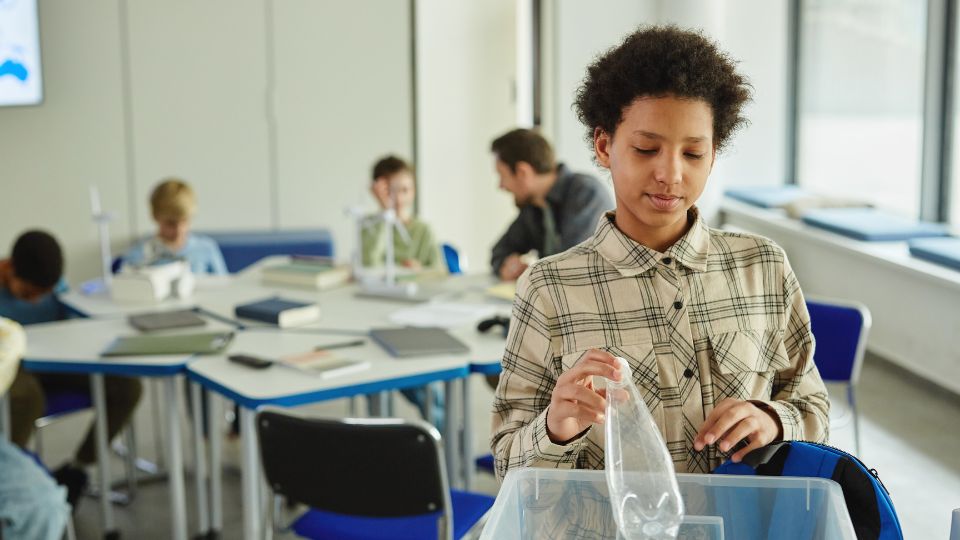 School child recycling plastic in classroom