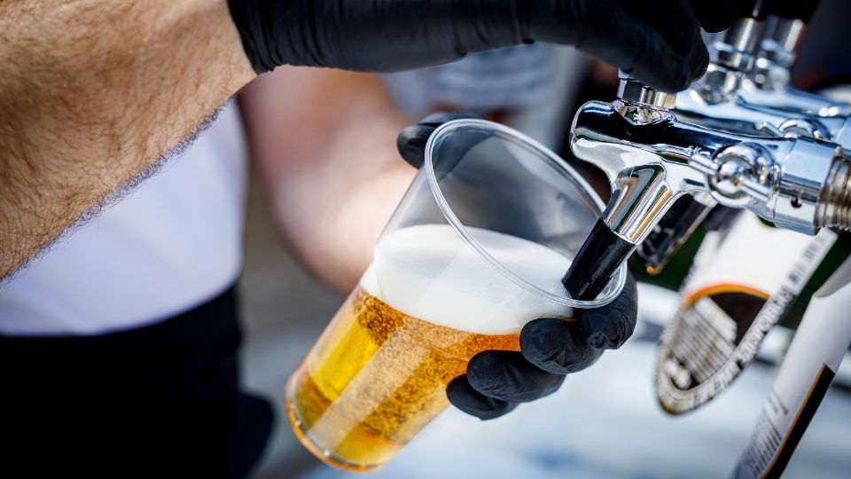 Plastic cup being refilled with beer.