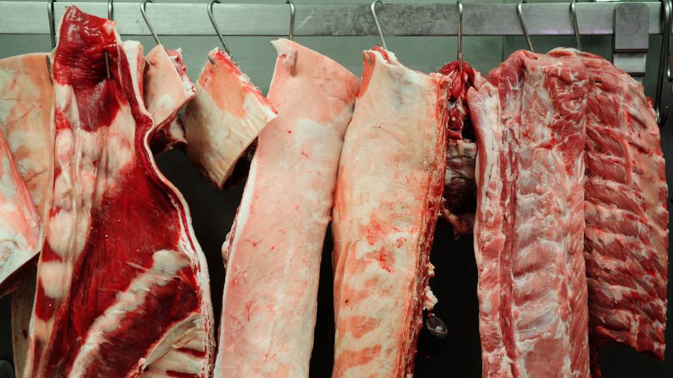 meat in a butchers hanging from meat hooks
