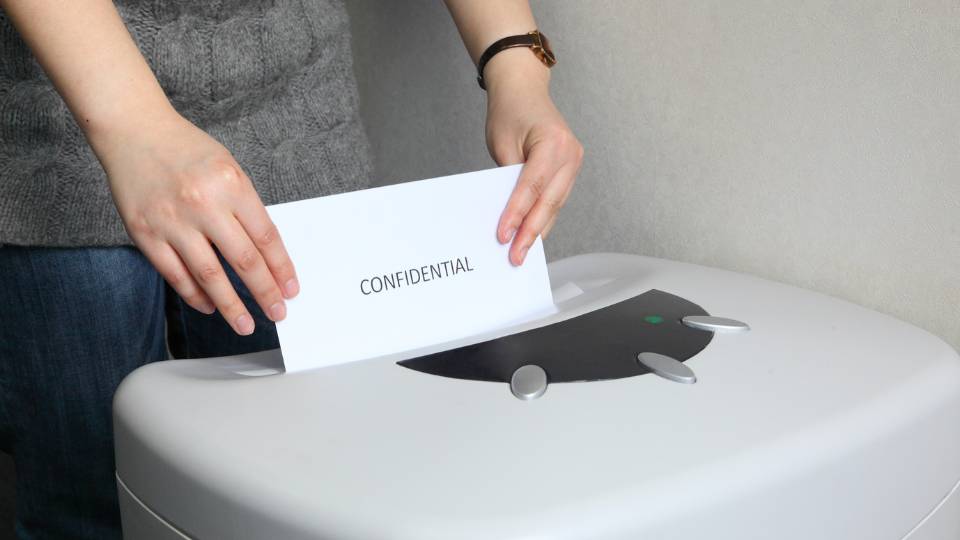 member of staff shredding confidential waste