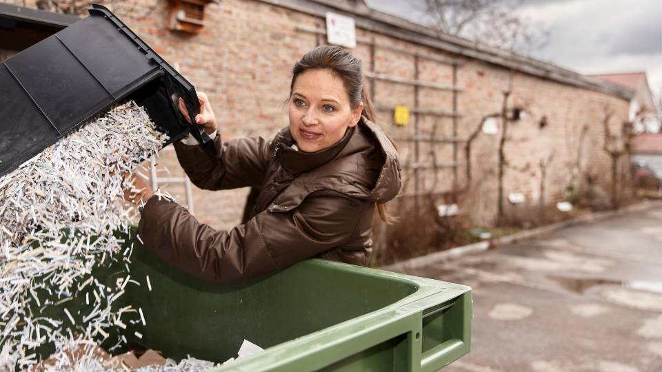 an employee disposing of confidential shredding in their recycling bin