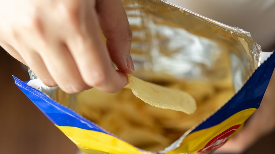 someone eating crisps from a non-recyclable crisp packet