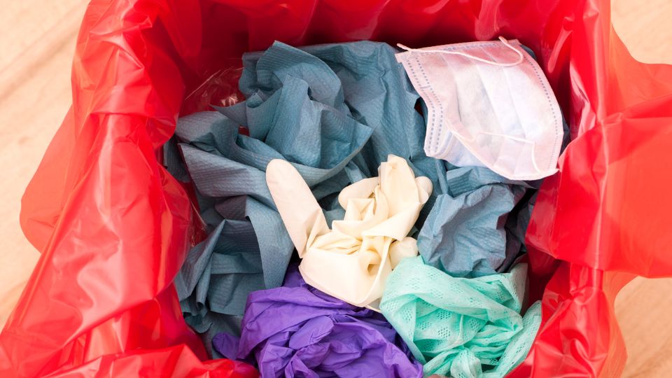 Clinical waste bin that contains plastic gloves and blue roll.