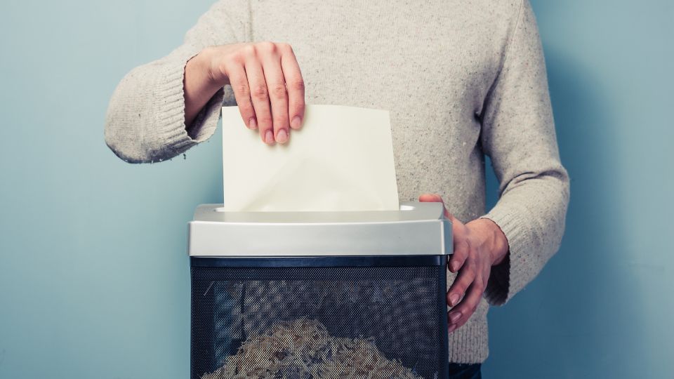 Person shredding confidential waste documents.