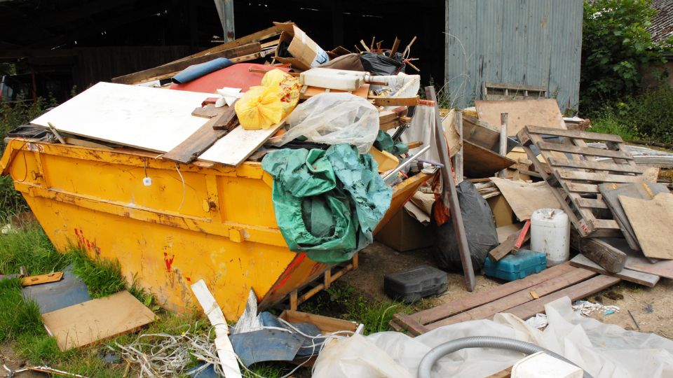 Yellow skip with waste overflowing.