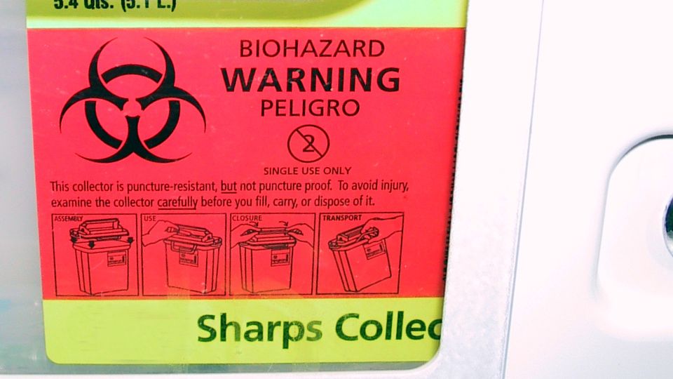 Biohazard label on a sharps collection bin.