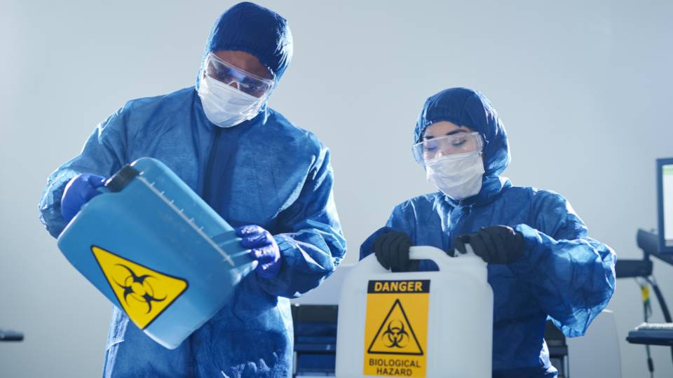 two hospital workers disposing of clinical waste correctly