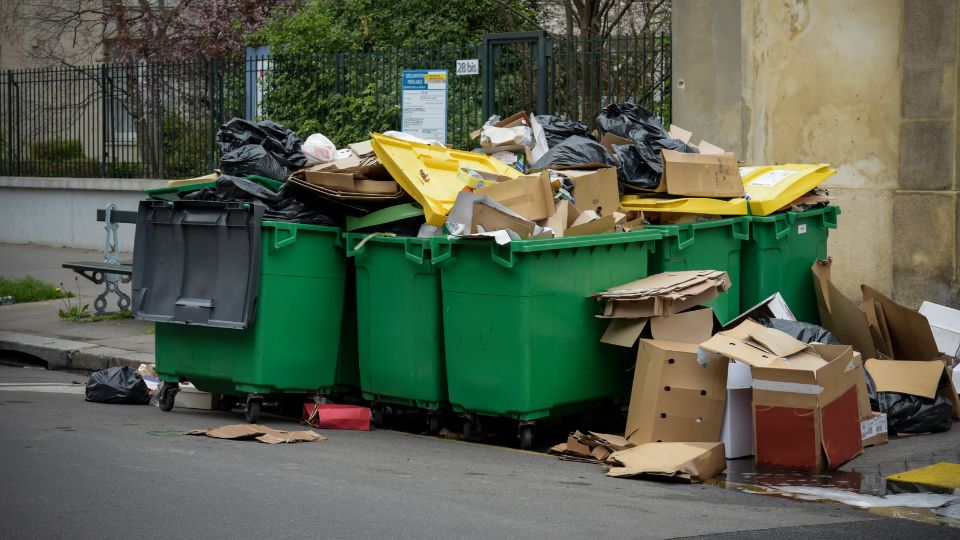 Overfilled large green wheelie bins in the street