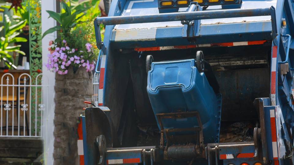 a commercial waste bin being collected by a bin lorry